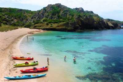 Kayaks en la playa de Es Grau, Menorca — aguas turquesas y acantilados